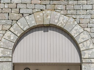 An archway made of stone blocks with a wooden panel backing at Berts Cottage in Heights near Appleby-in-Westmorland