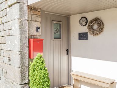 A front door with a small window and a red mailbox next to a stone wall at Berts Cottage in Heights near Appleby-in-Westmorland