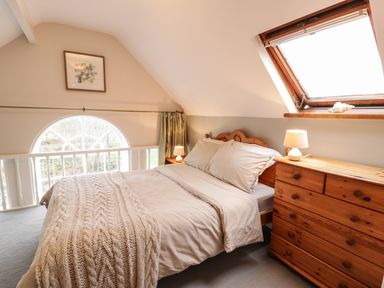 A bedroom with a wooden bed and chest of drawers under a skylight window at Is Y Deri in Harlech