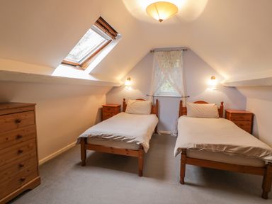 A bedroom with two single beds wooden furniture and a skylight window at Is Y Deri in Harlech