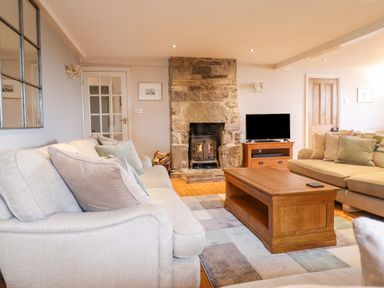 A living room with stone fireplace wooden coffee table and sofas at Is Y Deri in Harlech