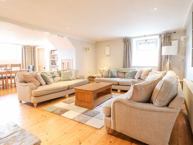 A living room with beige sofas and a wooden coffee table at Is Y Deri in Harlech