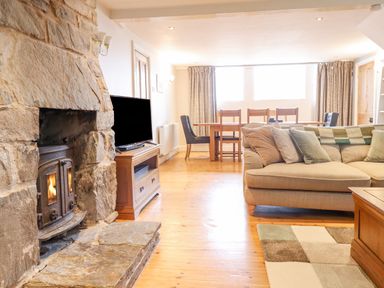 A living room with a stone fireplace sofa and dining table at Is Y Deri in Harlech