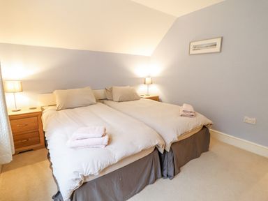 A bedroom with two single beds bedside tables and lamps at Is Y Deri in Harlech