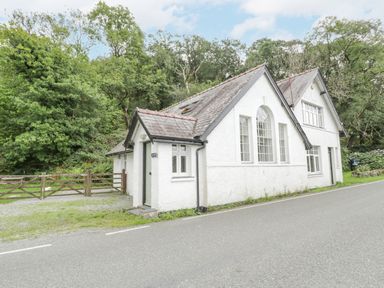 A white house with multiple windows and a gated entrance by the road at Is Y Deri in Harlech