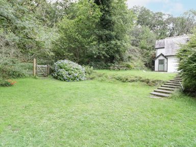 A garden with grass steps and a wooden gate next to a house at Is Y Deri in Harlech