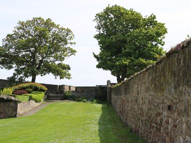 A grassy area with stone walls on both sides and trees at Iona 10 Palace Street East in Berwick-upon-Tweed
