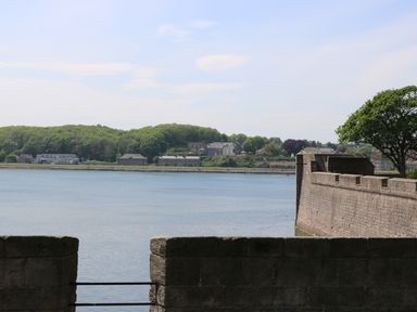 A waterfront view with stone walls trees and houses across the water at Iona 10 Palace Street East in Berwick-upon-Tweed