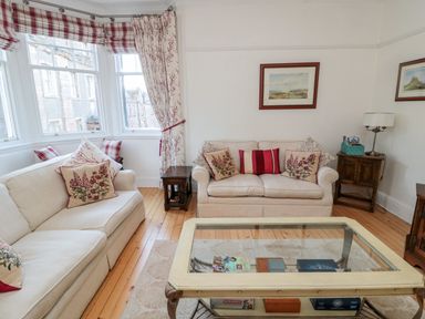 A living room with beige sofas and floral cushions wooden side tables and a glass coffee table at Iona 10 Palace Street East Berwick-upon-Tweed
