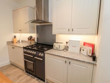 A kitchen with a stove toaster bread box and cutting boards at Iona 10 Palace Street East in Berwick-upon-Tweed