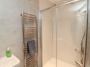 A bathroom with a shower cubicle a metal towel rack with a towel and a hand wash bottle at Iona 10 Palace Street East in Berwick-upon-Tweed
