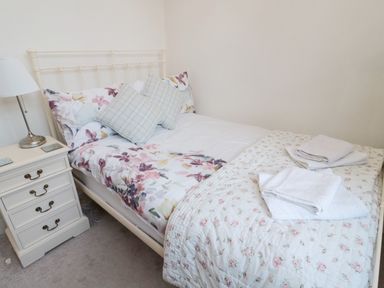 A bedroom with a bed covered with floral bedding and pillows beside a nightstand with a lamp at Iona 10 Palace Street East in Berwick-upon-Tweed