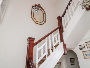 A staircase with wooden handrails and white balusters with a mirror above at Iona 10 Palace Street East in Berwick-upon-Tweed