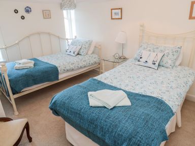 A bedroom with two single beds with blue floral bedding and blue throws at Iona 10 Palace Street East in Berwick-upon-Tweed