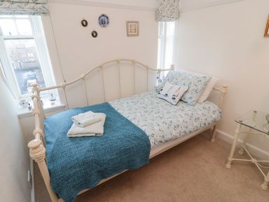 A bedroom with a bed covered in blue and white bedding and a folded towel on top at Iona 10 Palace Street East in Berwick-upon-Tweed