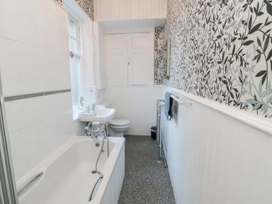 A bathroom with a bathtub toilet and sink and a patterned wall at Iona 10 Palace Street East in Berwick-upon-Tweed