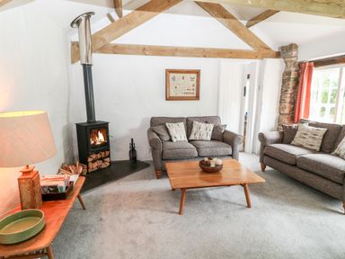A living room with two gray sofas a wooden coffee table and a wood burning stove at Treverbyn Smithy in St Neot