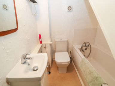 A bathroom with a sink, toilet, bathtub, and mirror at Treverbyn Smithy in St Neot