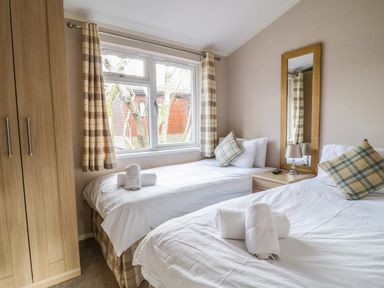 A bedroom with two single beds a wooden wardrobe and a window at 22 Thirlmere in Troutbeck Bridge