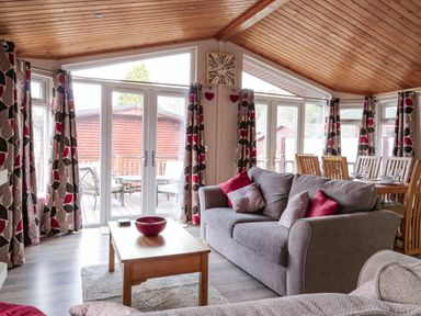 A living room with sofas a wooden table and dining table with chairs at 22 Thirlmere Troutbeck Bridge