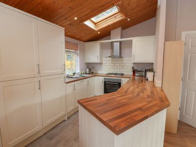 A kitchen with white cabinets wooden countertops and a skylight at 22 Thirlmere in Troutbeck Bridge