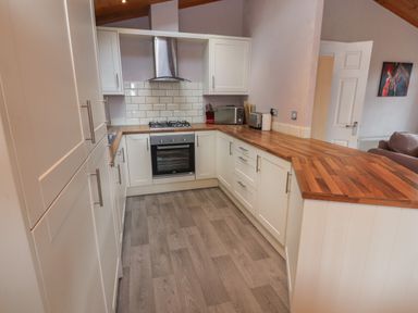 A kitchen with white cabinets wooden countertops gas stove oven and various appliances at 22 Thirlmere in Troutbeck Bridge