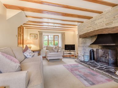 A living room with sofas a stone fireplace wooden beams and a television at West End Barn in Cleeve Prior near Evesham