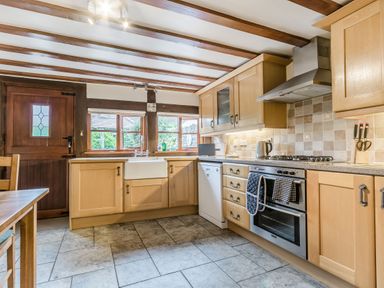 A kitchen with wooden cabinets tiled floor and built in oven at West End Barn in Cleeve Prior near Evesham