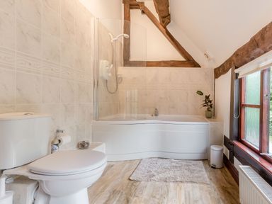 A bathroom with a toilet bathtub and shower next to a window at West End Barn in Cleeve Prior near Evesham