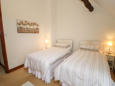 A bedroom with two single beds two bedside tables two lamps and a painting on the wall at West End Barn in Cleeve Prior near Evesham