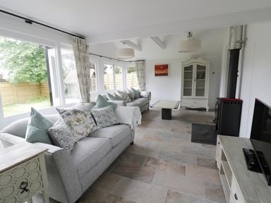 A living room with two gray sofas with cushions a coffee table a white cabinet a wood-burning stove and a television at Pebworth Cottage Pebworth near Stratford-upon-Avon
