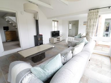 A living room with sofas coffee table TV and wood stove at Pebworth Cottage Pebworth near Stratford-upon-Avon
