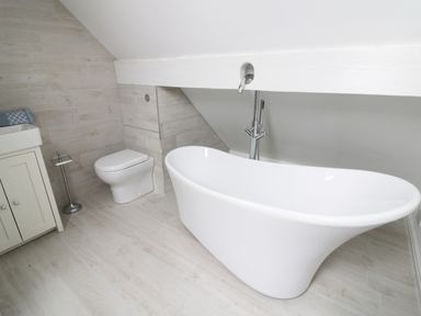 A bathroom with a freestanding bathtub a toilet a sink and a towel on a cabinet at Pebworth Cottage Pebworth near Stratford-upon-Avon