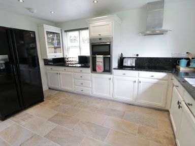 A kitchen with white cabinets black countertops and a black refrigerator at Pebworth Cottage in Pebworth near Stratford-upon-Avon