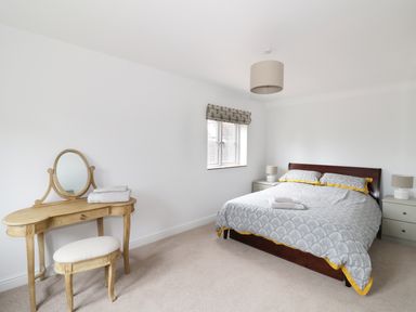 A bedroom with a bed nightstands a window and a vanity table with a stool at Pebworth Cottage Pebworth near Stratford-upon-Avon