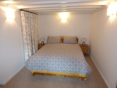 A bedroom with a double bed flanked by wooden nightstands and lamps at Pebworth Cottage in Pebworth near Stratford-upon-Avon