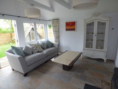 A living room with a grey sofa with cushions a coffee table a white cabinet and a painting at Pebworth Cottage in Pebworth near Stratford-upon-Avon