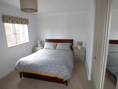A bedroom with a double bed between two bedside tables with lamps and a window on the left at Pebworth Cottage Pebworth near Stratford-upon-Avon