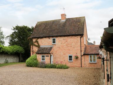 A brick house with a tiled roof and gravel driveway at Pebworth Cottage Pebworth near Stratford-upon-Avon