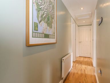 A hallway with wood flooring a radiator and a framed map on the wall at Claife View Lodge in Troutbeck Bridge