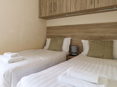 A bedroom with two single beds white linens and folded towels at Claife View Lodge in Troutbeck Bridge