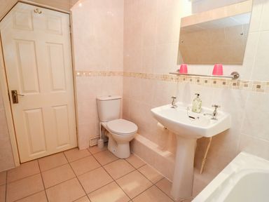 A bathroom with a toilet sink mirror and door at Rosemary Cottage in Bourton-on-the-Water