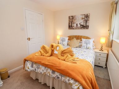 A bedroom with a bed with animal print bedding and two folded towels on an orange blanket at Rosemary Cottage in Bourton-on-the-Water