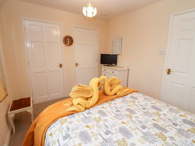 A bedroom with a bed with animal print bedding and two towel swans on top at Rosemary Cottage in Bourton-on-the-Water