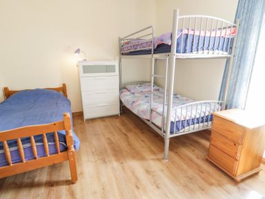 A bedroom with a wooden single bed a metal bunk bed a white chest of drawers and a wooden nightstand at Creeslough View in Creeslough near Glenveagh National Park County Donegal