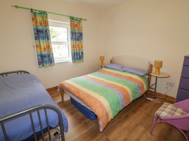 A bedroom with two beds one with multicolored striped bedding and one with blue bedding and colorful curtains at Creeslough View in Creeslough near Glenveagh National Park County Donegal