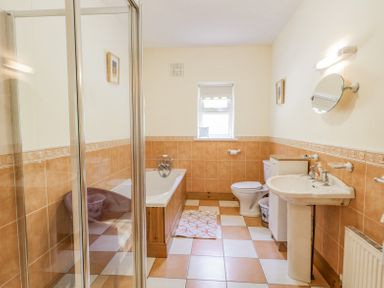 A bathroom with a shower enclosure bathtub toilet sink and a small window at Creeslough View in Creeslough near Glenveagh National Park County Donegal