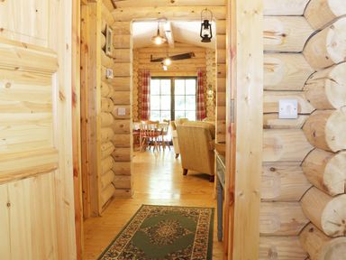 Hallway with a green patterned rug leading to a living and dining area in a wooden log cabin Wilderness Lodge in Stiperstones
