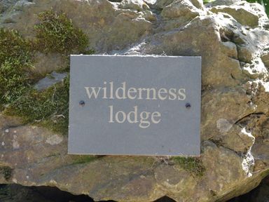 A stone plaque with the words wilderness lodge mounted on a rock with moss