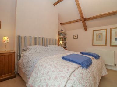 A bedroom with a double bed blue blankets wooden bedside tables lamps bookshelves and framed pictures at Drover's Sutton Mallet